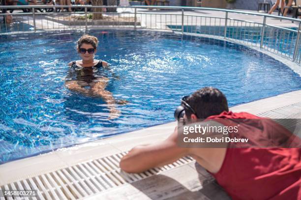 a man and a woman at an outdoor pool in a hotel. - swimwear singlet stock pictures, royalty-free photos & images
