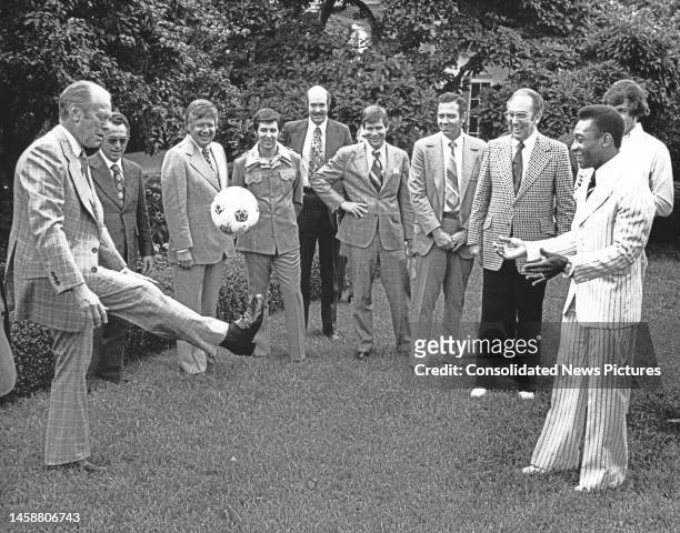 President Gerald Ford watches as Brazilian soccer player Pele bounces a soccer ball on his head in the White House's Rose Garden, Washington DC, June...