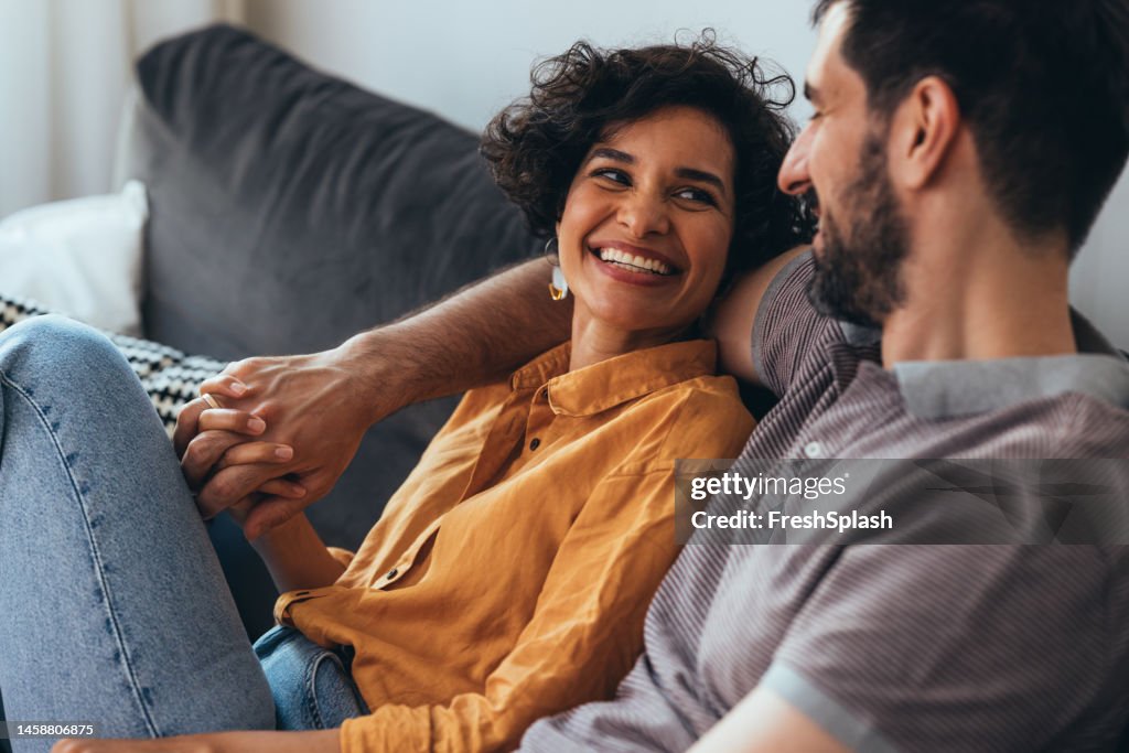 Ein glückliches schönes Paar, das zu Hause auf dem gemütlichen Sofa sitzt und sich entspannt