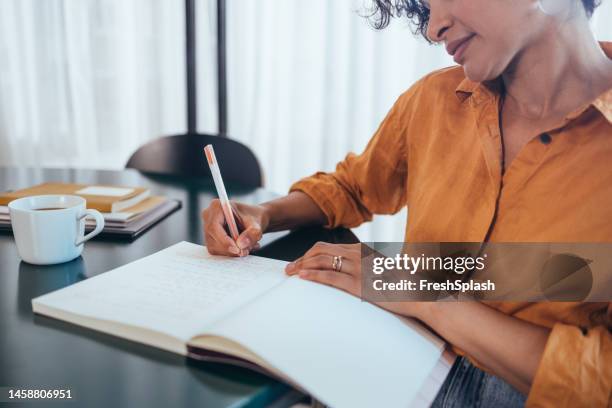 an unrecognizable happy beautiful businesswoman sitting in the office and working - yellow note pad stock pictures, royalty-free photos & images