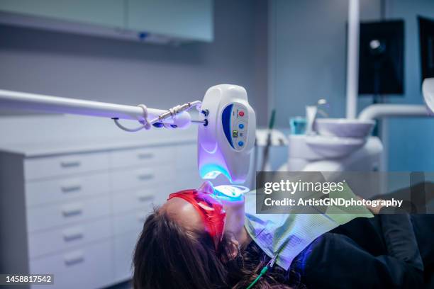 giovane donna che riceve un trattamento dentale sbiancante. - sbiancamento dentale foto e immagini stock
