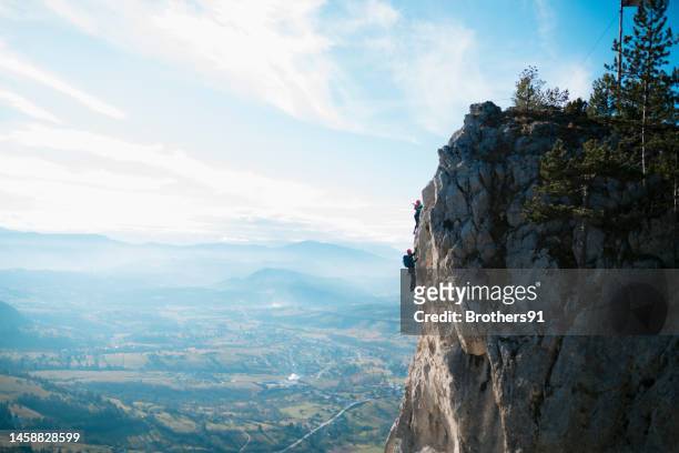 two mountaineers rock climbing a face of a cliff - hazard goal stock pictures, royalty-free photos & images