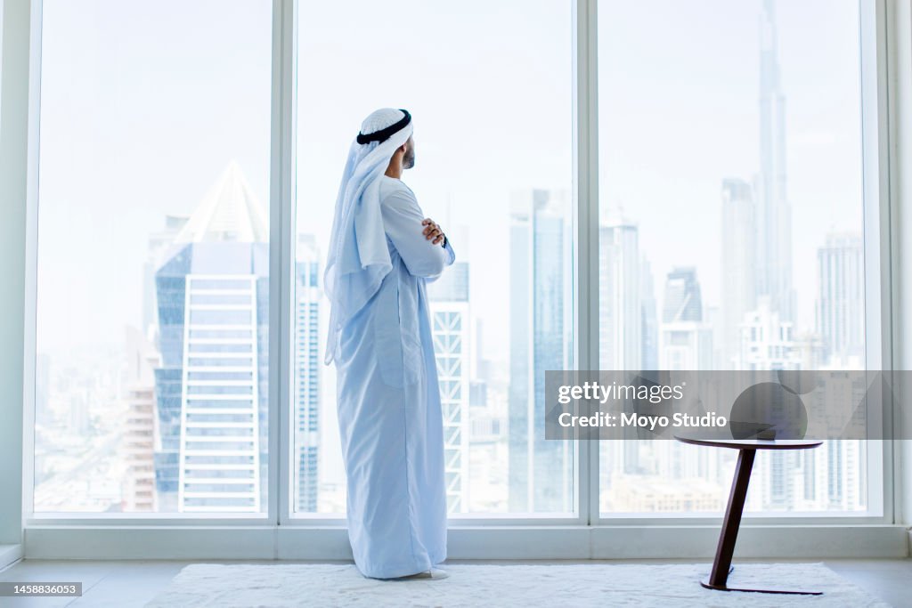 Seitenansicht eines arabischen Geschäftsmannes mit Blick durch Fenster in modernem Büro