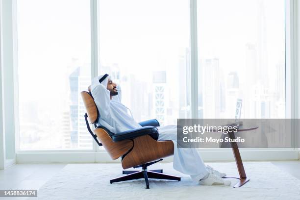 side view of arab man with beard relaxing on modern armchair in office with city view - arab culture stock pictures, royalty-free photos & images