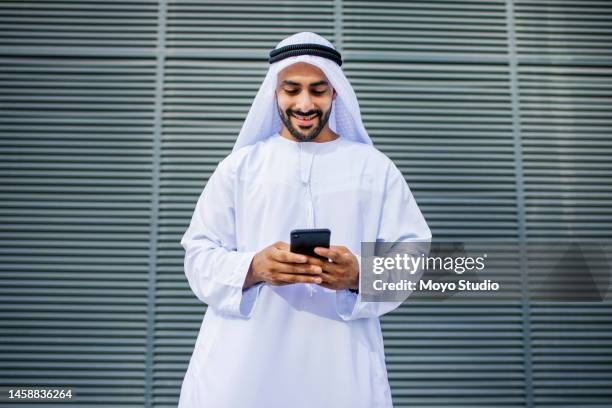 portrait of cheerful arab businessman texting on cellphone - uae heritage stock pictures, royalty-free photos & images