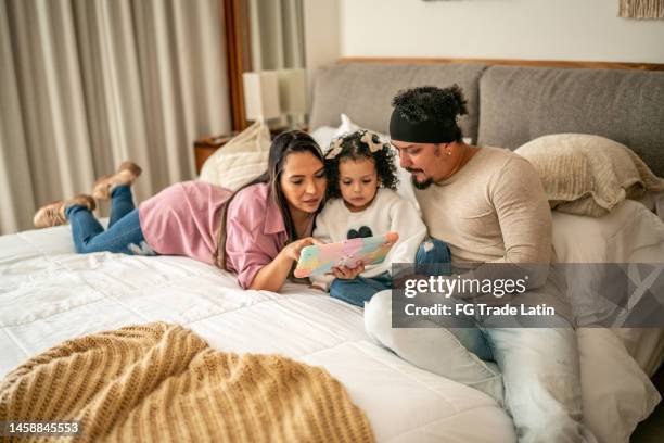 parents utilisant une tablette numérique avec leur fille dans la chambre à la maison - movie film reel photos et images de collection