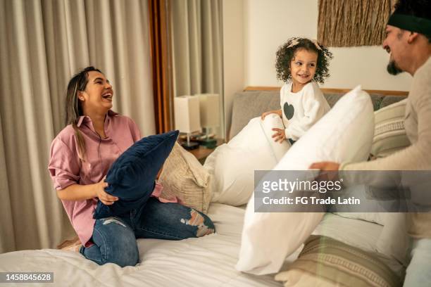 family having fun while fighting with pillow in the bedroom at home - father and child and pillow fight stock pictures, royalty-free photos & images
