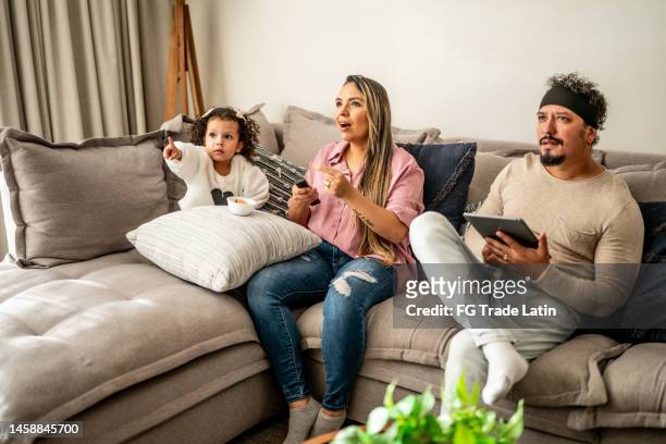 familia viendo la televisión en la sala de estar de casa - reality tv fotografías e imágenes de stock