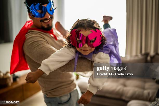 portrait of father and daughter playing superhero in the living room at home - costume players stock pictures, royalty-free photos & images