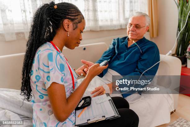 nurse tests her senior adult patient's high blood sugar with a glucometer - medical oxygen stock pictures, royalty-free photos & images