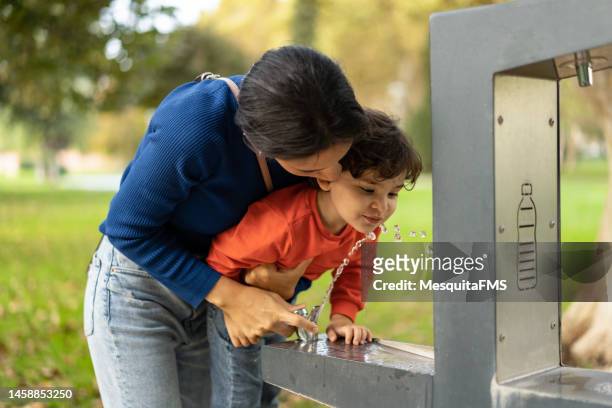 people drinking water from fountain in public park - drinking fountain stock pictures, royalty-free photos & images