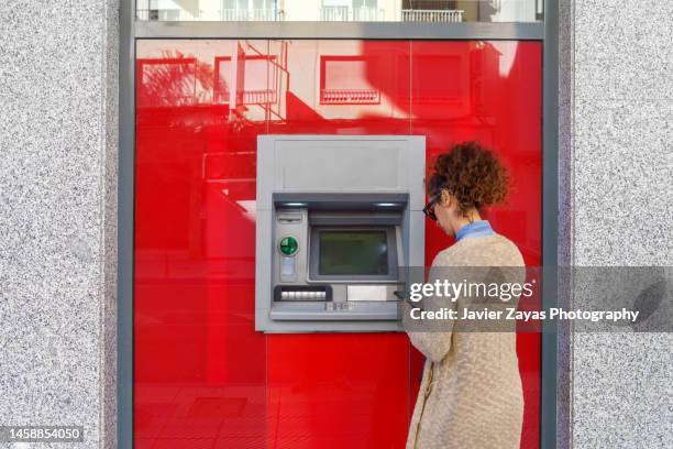 latin woman using atm - cajero fotografías e imágenes de stock