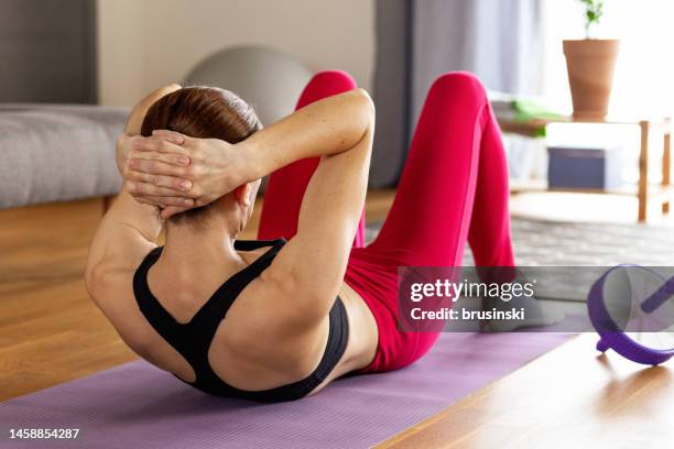 donna bianca di 40 anni che fa allenamento a casa - sit up foto e immagini stock