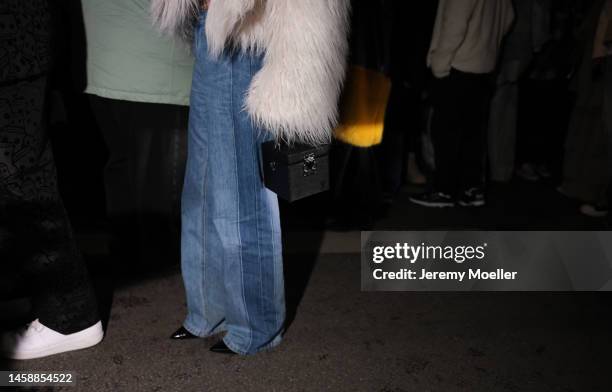 Fashion week guest seen wearing a black Louis Vuitton bag, a jean, a black croptop and a white fluffy fur jacket before the KidSuper show on January...