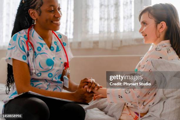 young home health nurse and the little girl with cancer embrace and laugh together. - girl hold nose stock pictures, royalty-free photos & images