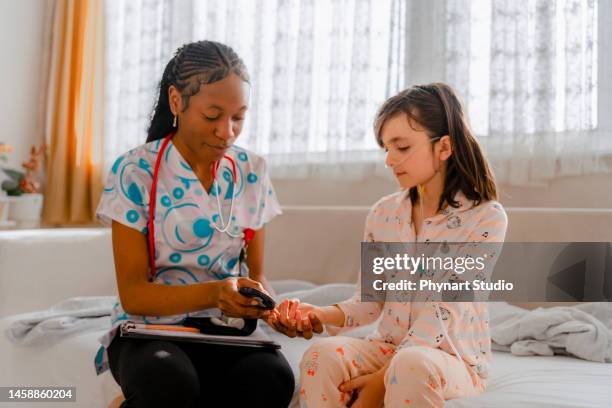 nurse tests her little patient's high blood sugar with a glucometer - childhood diabetes stock pictures, royalty-free photos & images