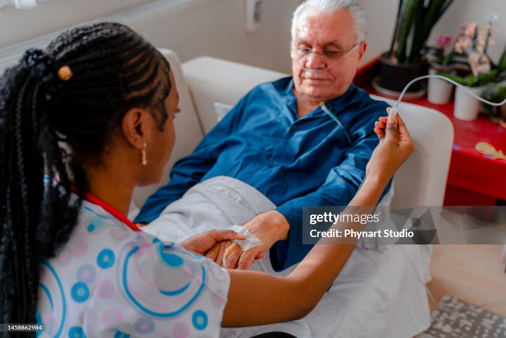 Krankenschwester befestigt IV-Tropf am Patienten
