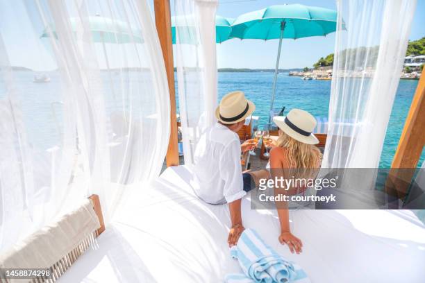 couple toasting with champagne on a luxurious day bed. - luxury hotel island stockfoto's en -beelden