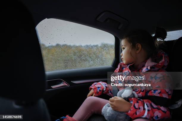 little girl travelling in car on a rainy day - girl rain night stock pictures, royalty-free photos & images