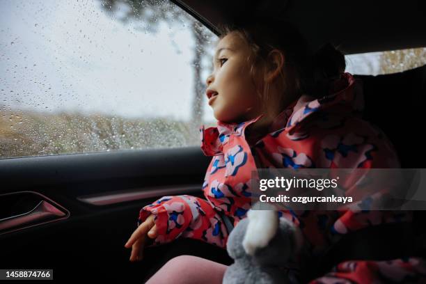 little girl travelling in car on a rainy day - girl rain night stock pictures, royalty-free photos & images