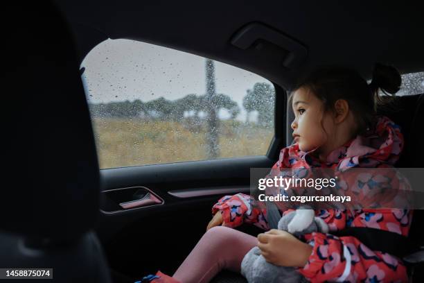 little girl travelling in car on a rainy day - girl rain night stock pictures, royalty-free photos & images