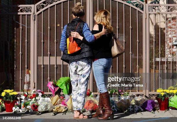 People embrace at a makeshift memorial outside the scene of a deadly mass shooting at a ballroom dance studio on January 23, 2023 in Monterey Park,...