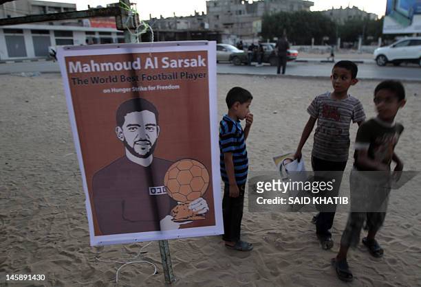 Palestinian children stand next to a picture of Palestinian football player Mahmoud Sarsak who has been held in Israeli jail since 2009, during a...