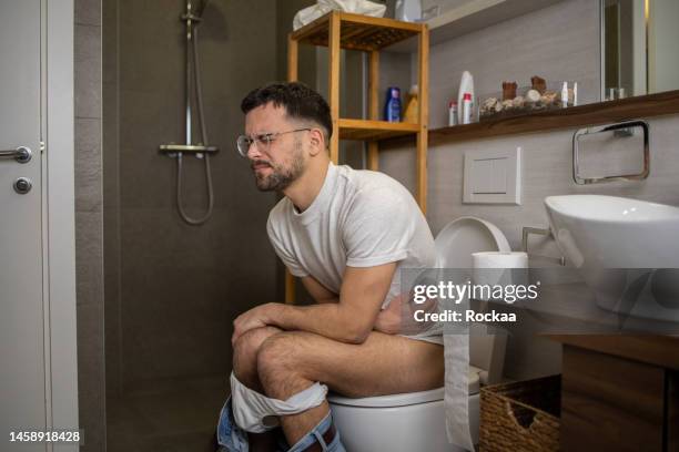 man sitting on toilet - diarree stockfoto's en -beelden