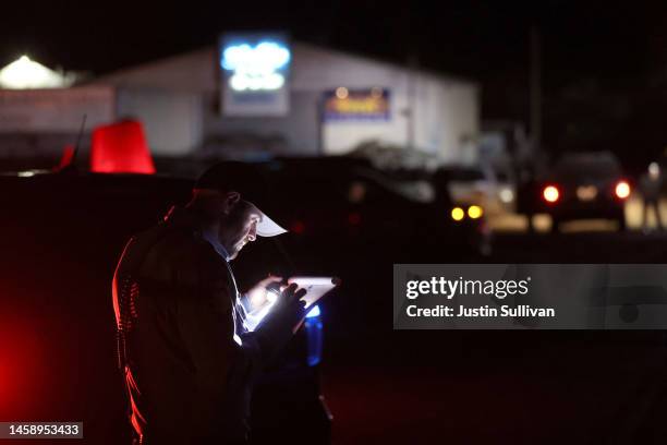 San Mateo County sheriff deputy does paperwork at the scene of a shooting on January 23, 2023 in Half Moon Bay, California. Seven people were killed...