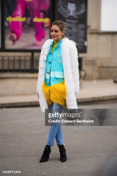Olivia Palermo wears silver and diamonds earrings, a yellow ribbed wool high neck pullover, diamonds necklaces, a blue flashy buttoned with...