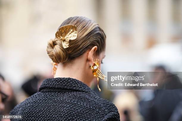 Chiara Ferragni wears gold large hair clip from Schiaparelli, gold large face pattern earrings from Schiaparelli, a black embossed pattern with puffy...