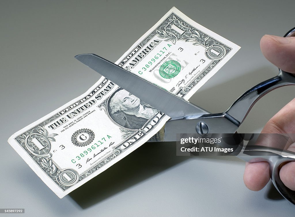 Dollar bill being cut with scissors