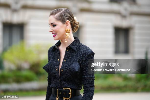 Chiara Ferragni wears gold large hair clip from Schiaparelli, gold large face pattern earrings from Schiaparelli, a black embossed pattern with puffy...