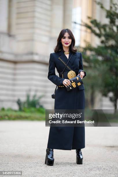 Heart Evangelista wears diamonds earrings, a gold large chain necklace from Tiffany, a black long coat from Schiaparelli, a black shiny leather with...