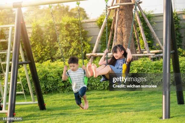 girl and boy swinging - swing play equipment stock pictures, royalty-free photos & images