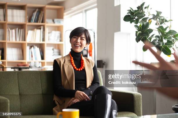 jovem empresária conversando com colegas em um escritório criativo. - mulher japonesa - fotografias e filmes do acervo