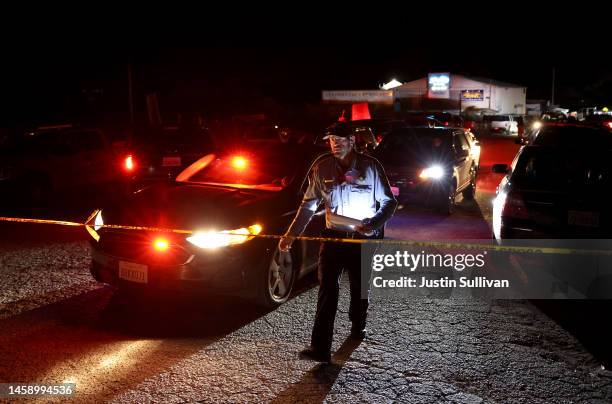 San Mateo County sheriff deputy walks towards police tape as law enforcement officials conduct an investigation following a mass shooting on January...