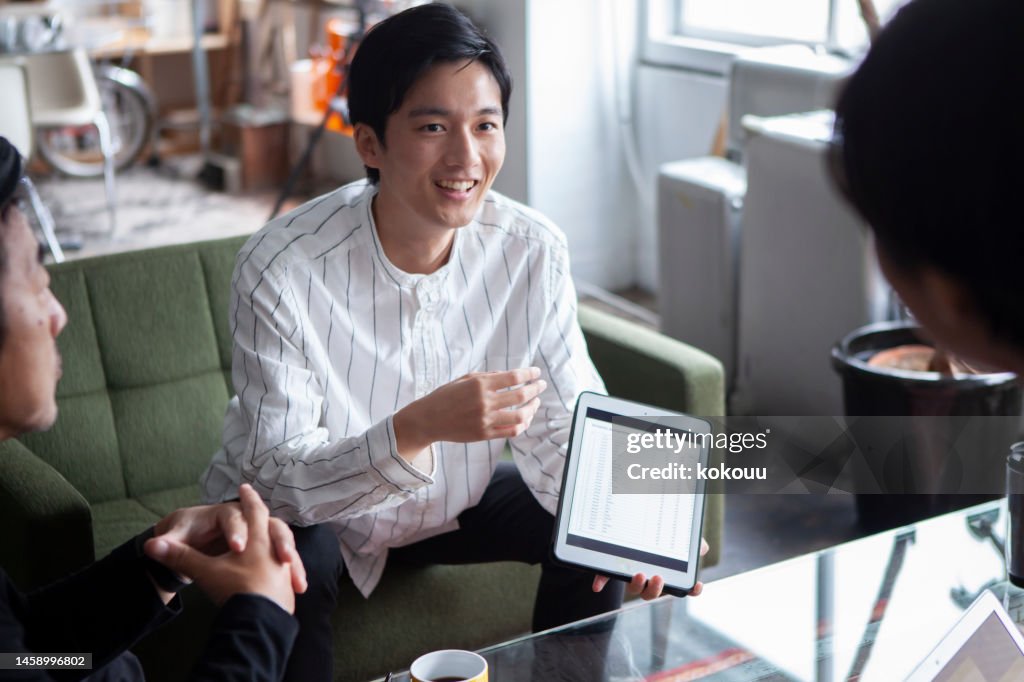 A young man plays a central role in a company meeting.