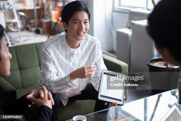 a young man plays a central role in a company meeting. - japanese ethnicity stock pictures, royalty-free photos & images