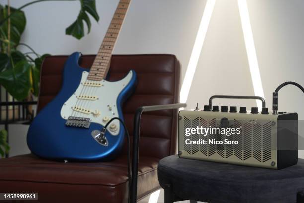an electric guitar on a tan leather chair with an amp next to it - guitare électrique photos et images de collection