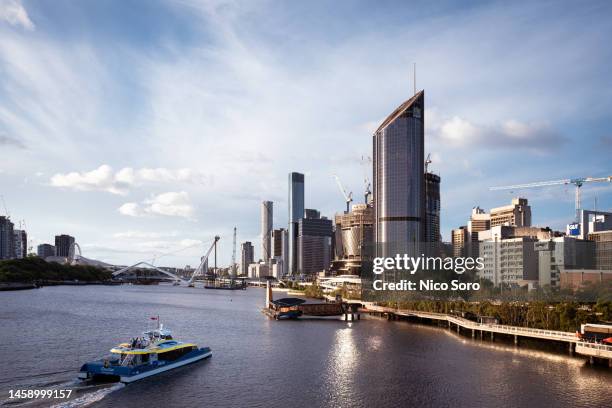 a ferry on the brisbane river with buildings in the background - brisbane stock-fotos und bilder