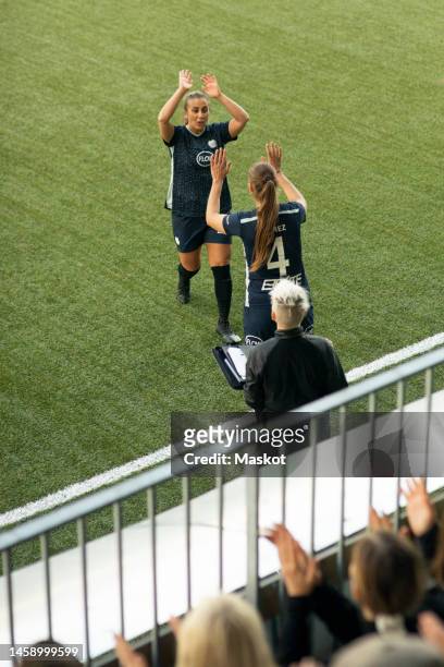 female soccer players giving high five to each other at football stadium - subs bench fotografías e imágenes de stock