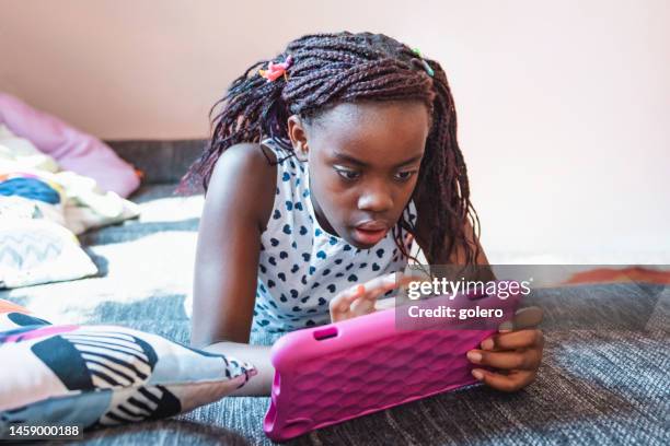 little girl looking at digital tablet on sofa - pop music imagens e fotografias de stock