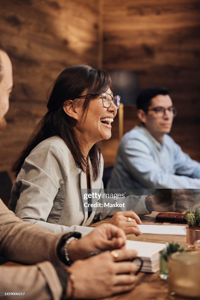 Mature businesswoman wearing eyeglasses laughing during meeting at office