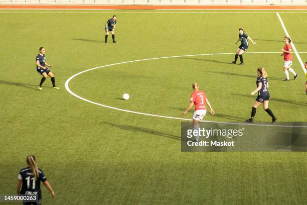 female soccer players playing with each other during match in sports stadium - fussball pass stock-fotos und bilder
