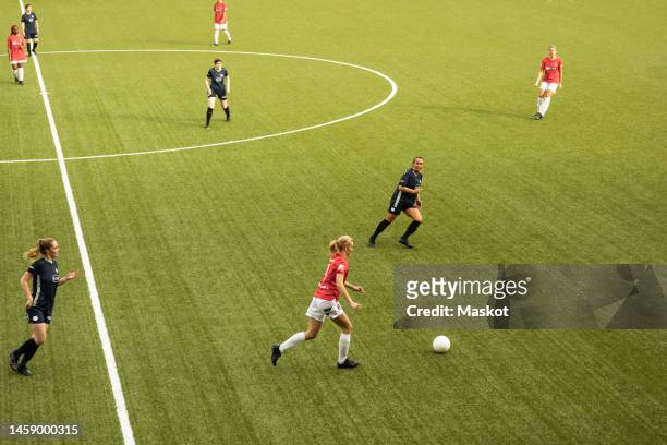 female soccer players running while playing with each other during competition in stadium - passing sport stock pictures, royalty-free photos & images