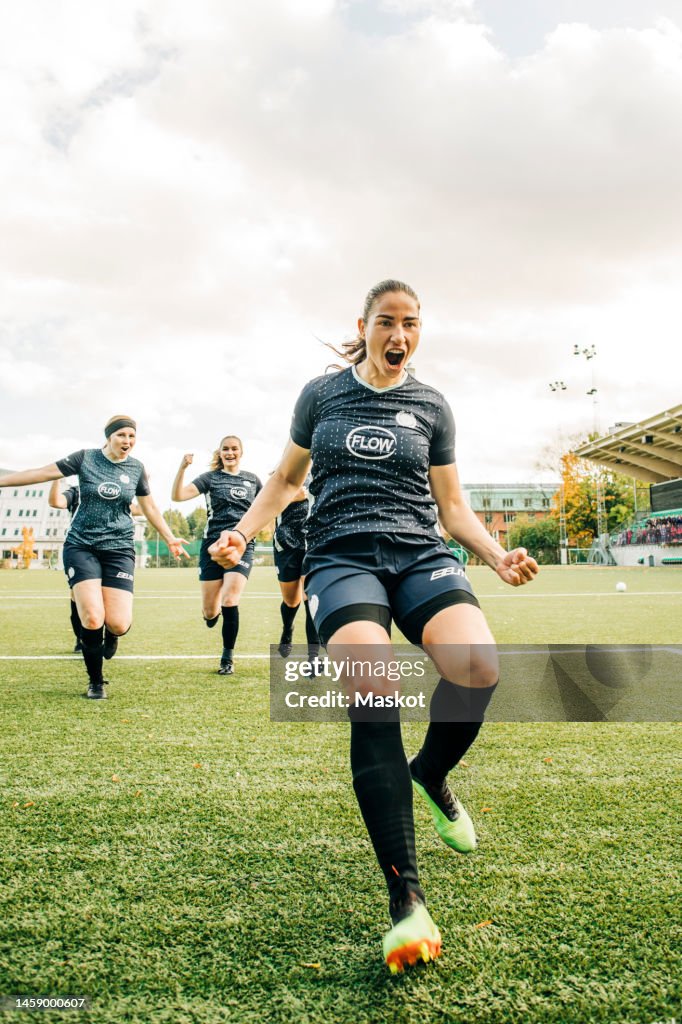 Female soccer player celebrating goal with team during match in stadium