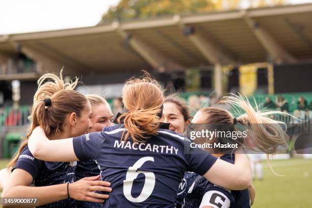 excited female player huddling with soccer team celebrating win in stadium - huddle sport girls stock pictures, royalty-free photos & images