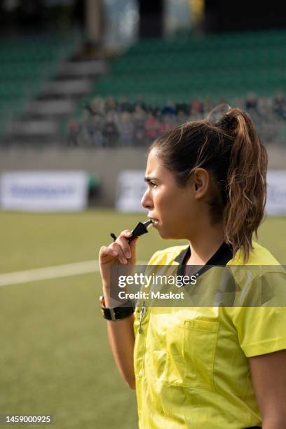 female referee blowing whistle during soccer match in stadium - soccer referee fotografías e imágenes de stock