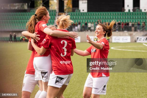 happy female players celebrating together during soccer match in stadium - voetbal fotos stockfoto's en -beelden